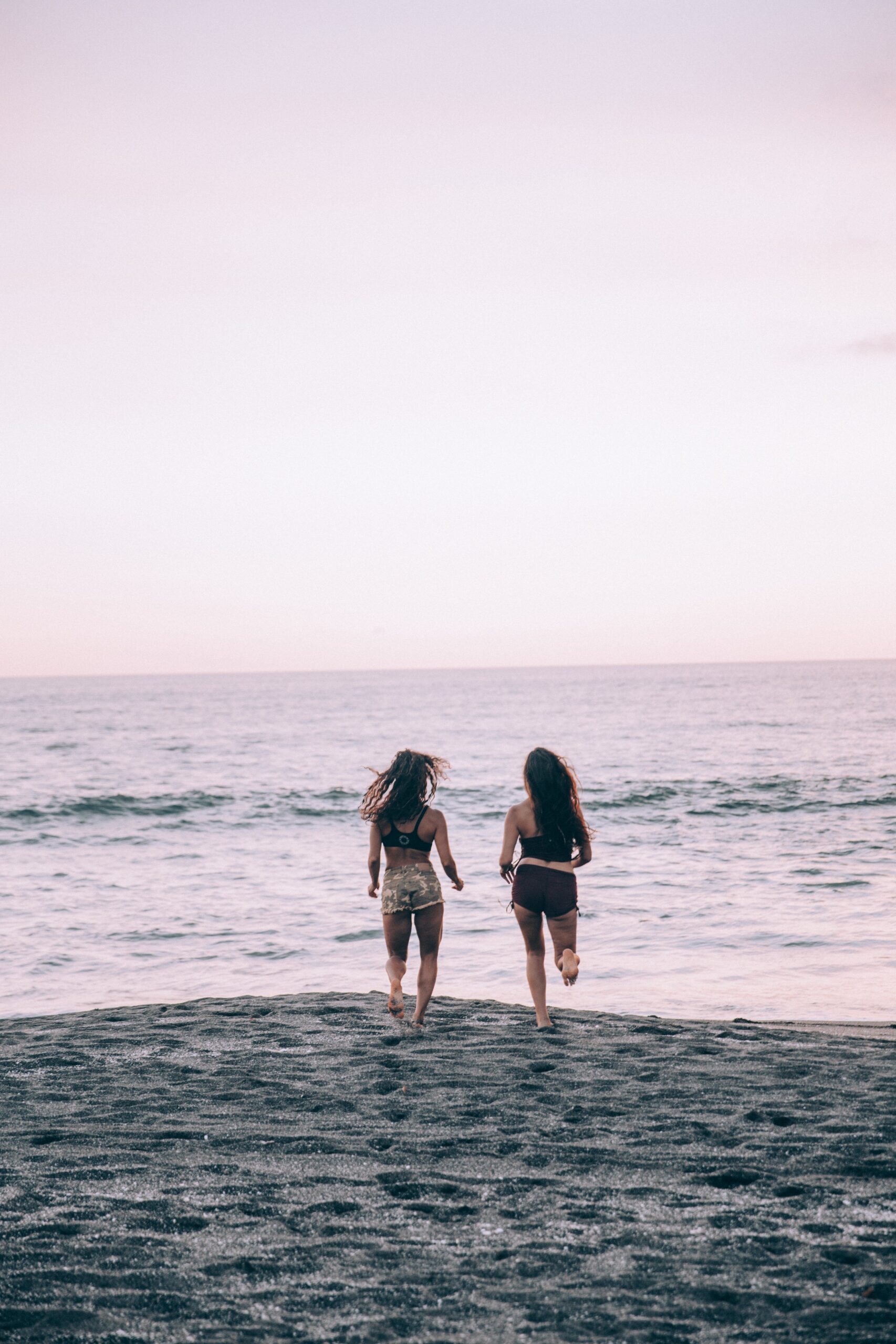 two-women-run-along-a-sunset-beach